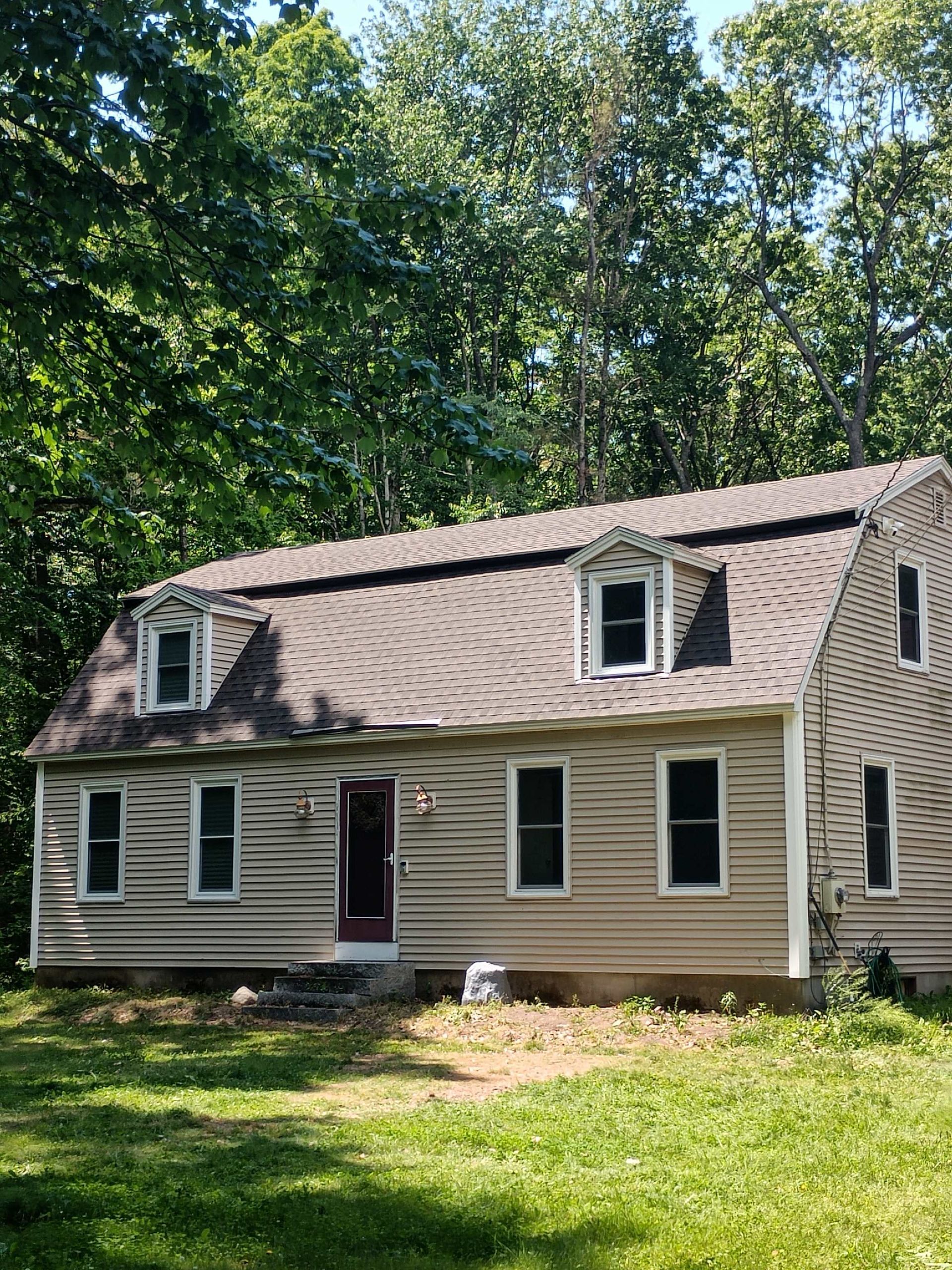 A house with a roof that is surrounded by trees and grass.
