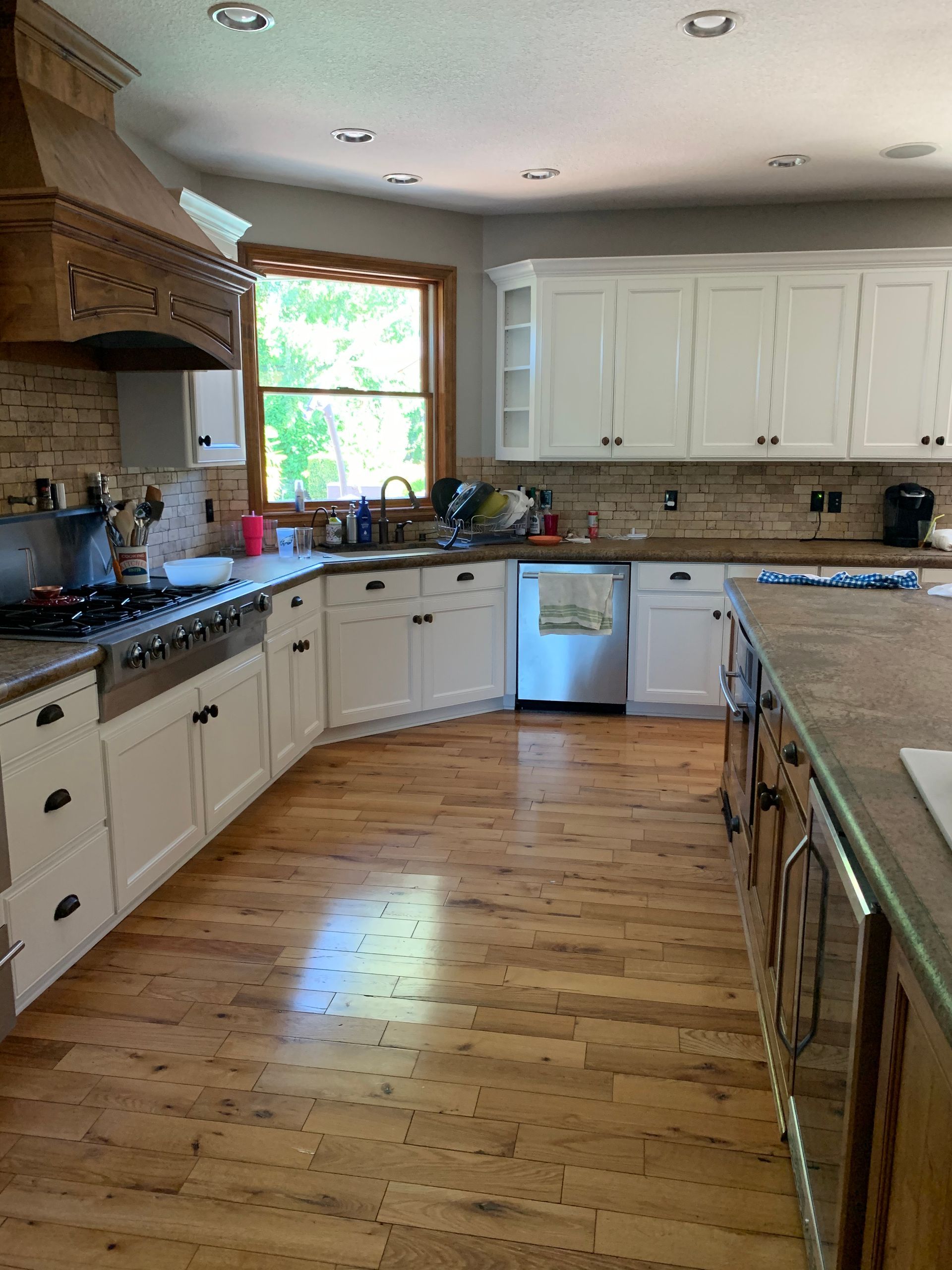 Kitchen with white cabinets, wood floors, and a large island. Stainless steel appliances.