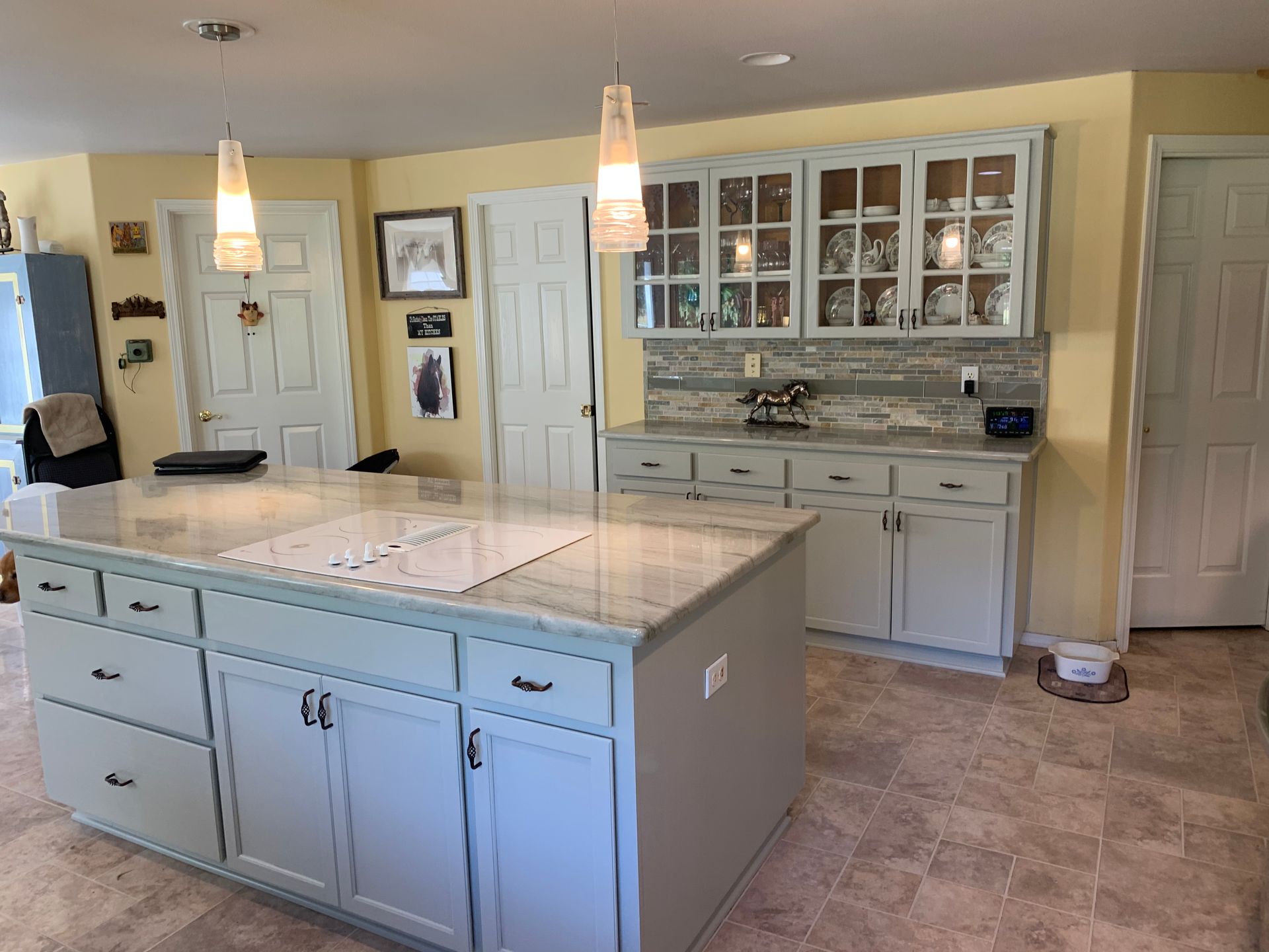Kitchen with a large island and light blue cabinetry, neutral countertops, and pendant lighting.
