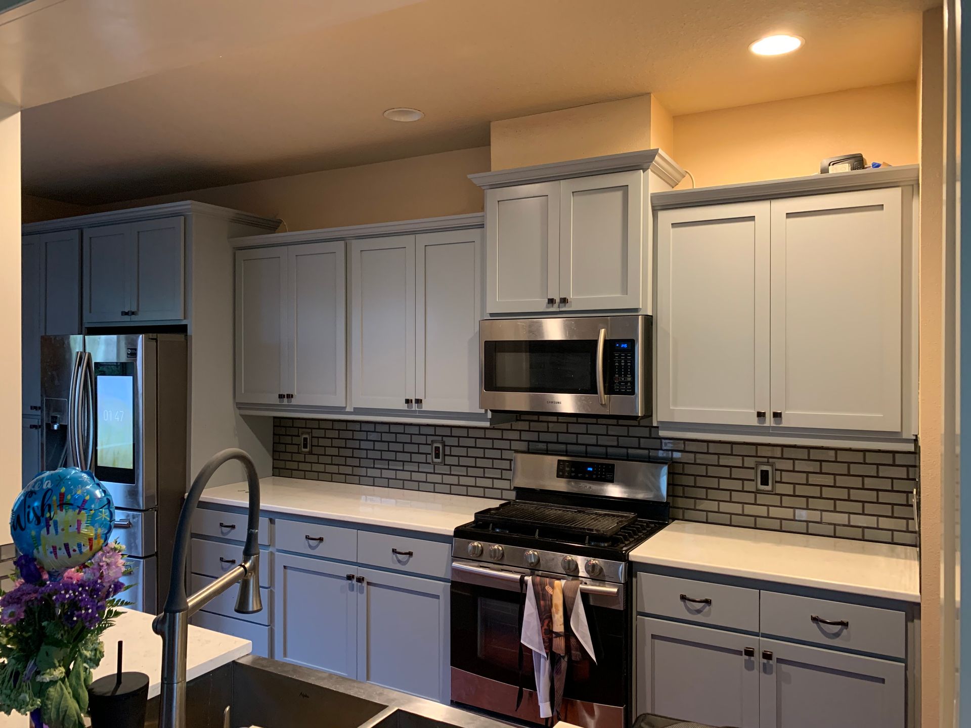 Kitchen with light blue cabinets, stainless steel appliances, and a gray brick-patterned backsplash.