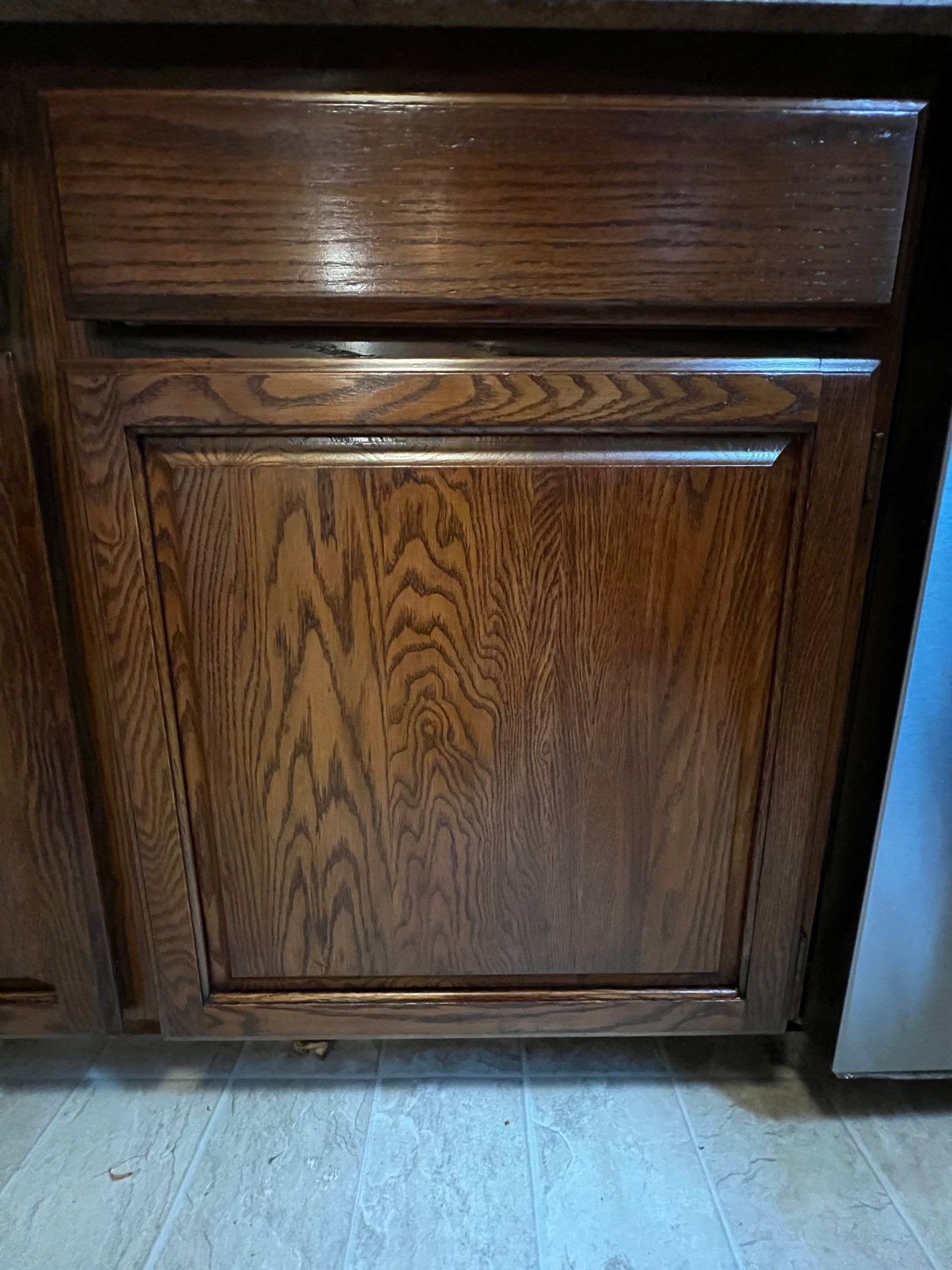 Wooden kitchen cabinet with a stained, textured surface.