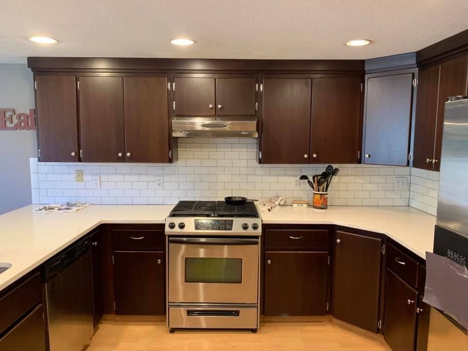 Kitchen with dark brown cabinets, stainless steel appliances, and white countertops.