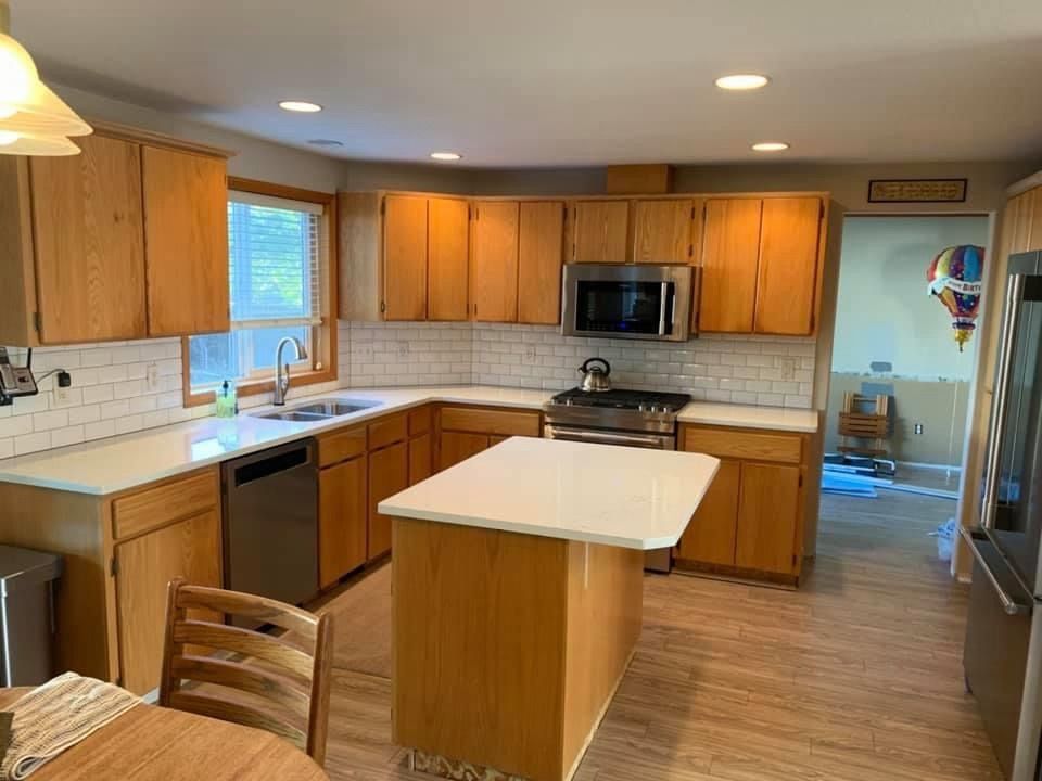 Kitchen with light wood cabinets, white countertops, subway tile backsplash, and stainless steel appliances.