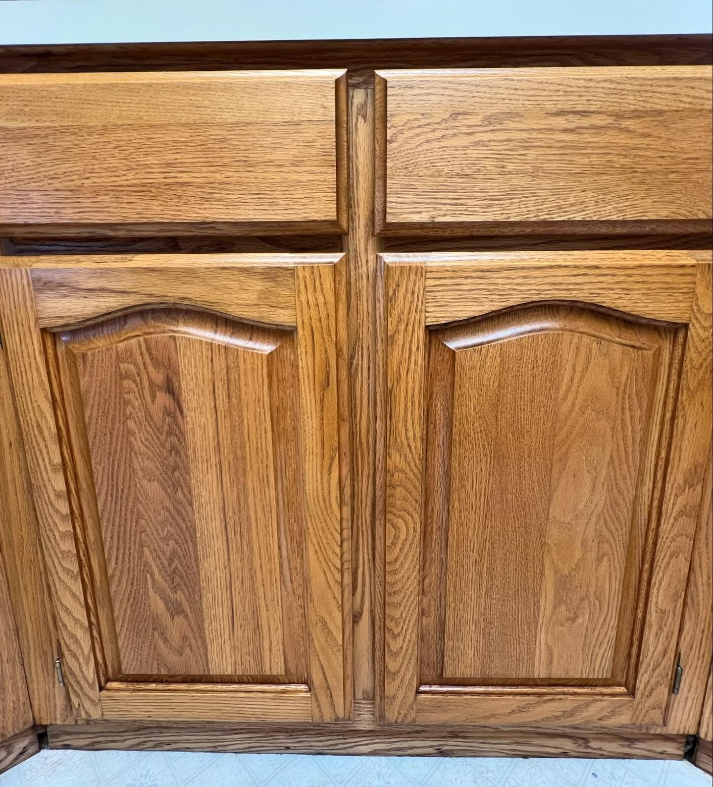 Wooden kitchen cabinet with two upper drawers and two arched panel doors.