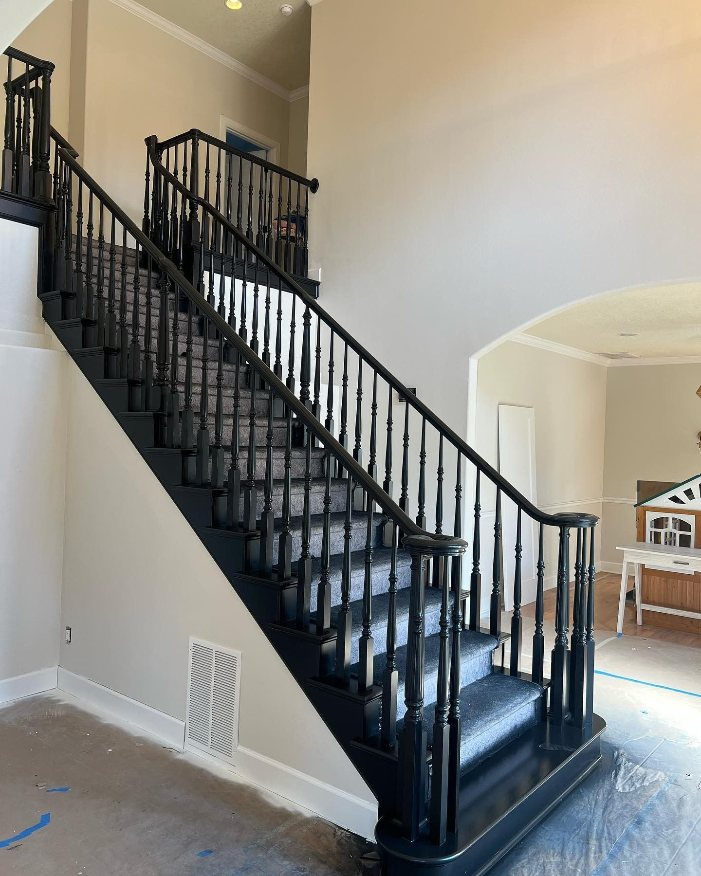 Black staircase with matching spindles and handrail, carpeted steps, white walls.