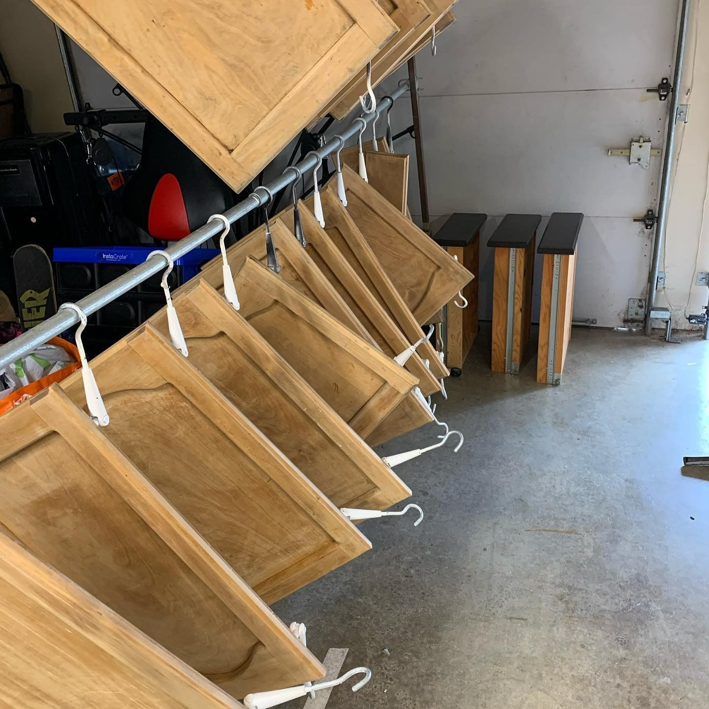 Cabinet doors hanging on a metal rod. Garage setting with gray floor and closed door.