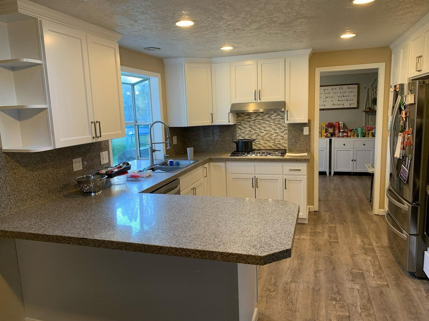 White kitchen cabinets and countertops with a stone backsplash.