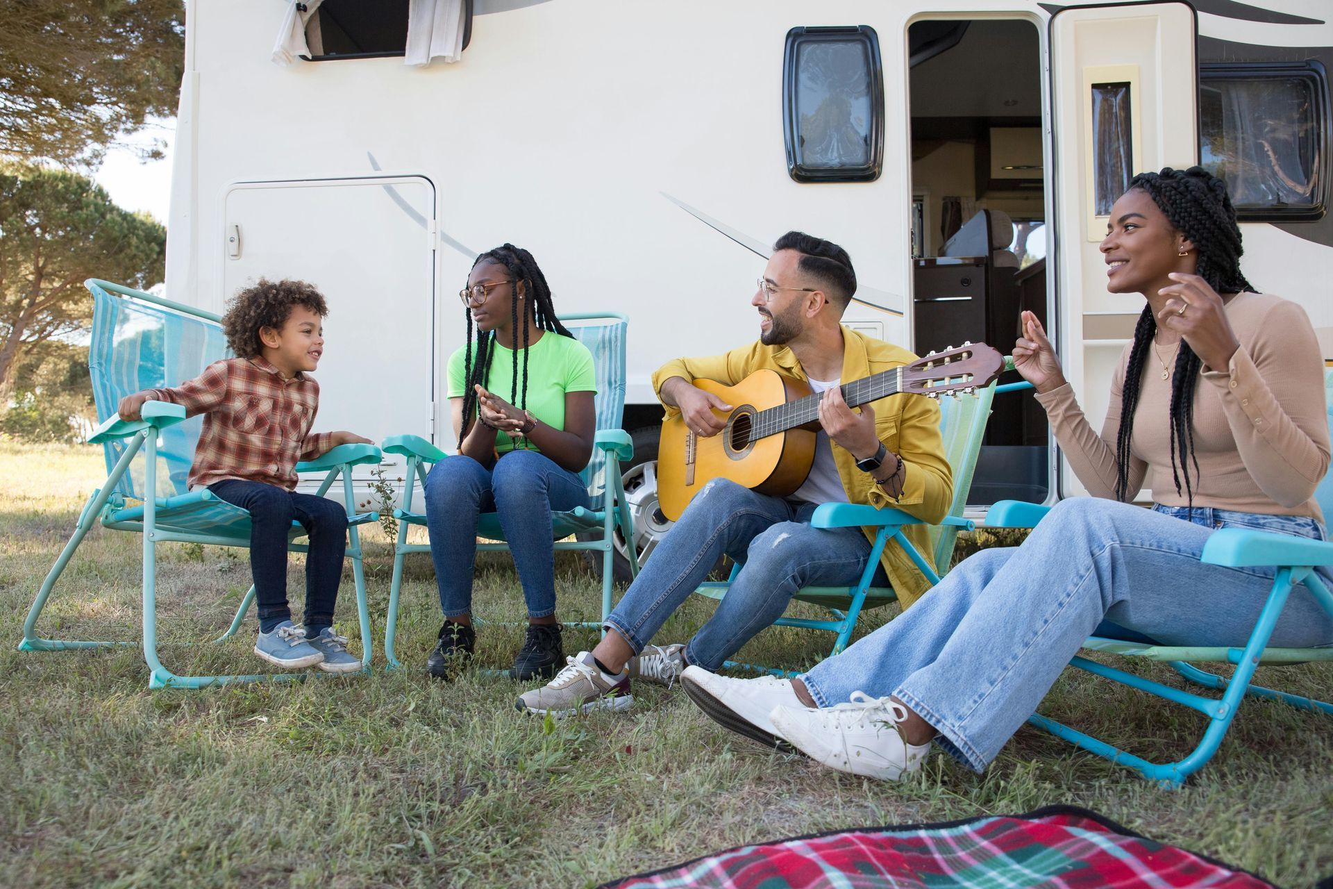 Family camping outdoors near a camper.