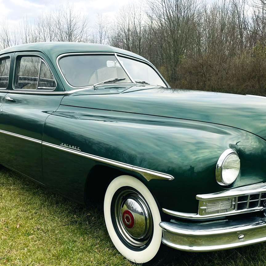 A man is polishing the hood of a blue car