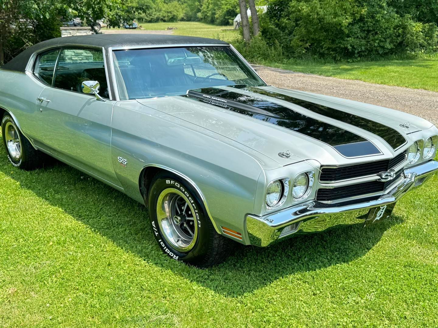 A silver chevrolet chevelle is parked in the grass.