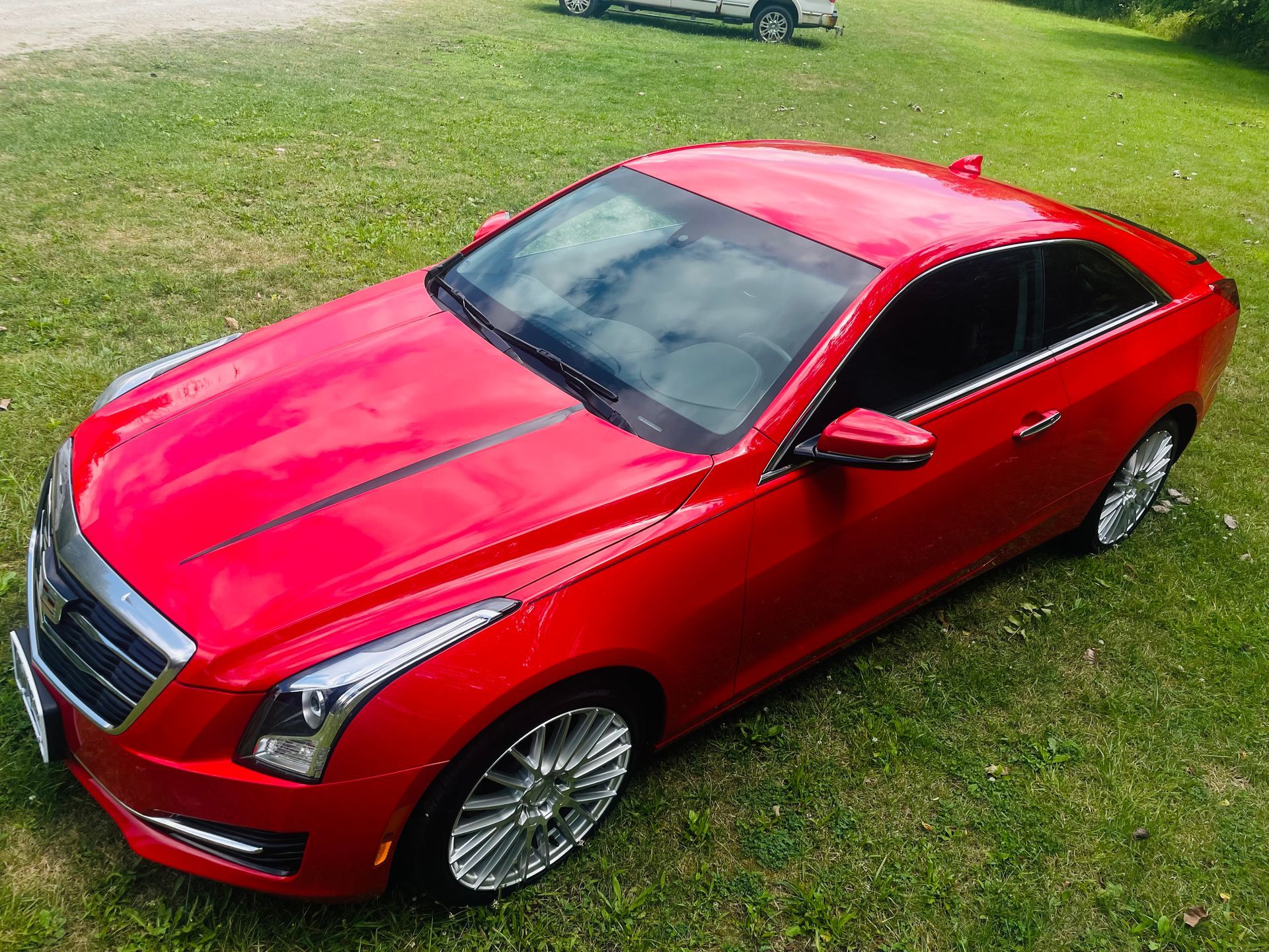 Red Cadillac coupe parked on green grass.