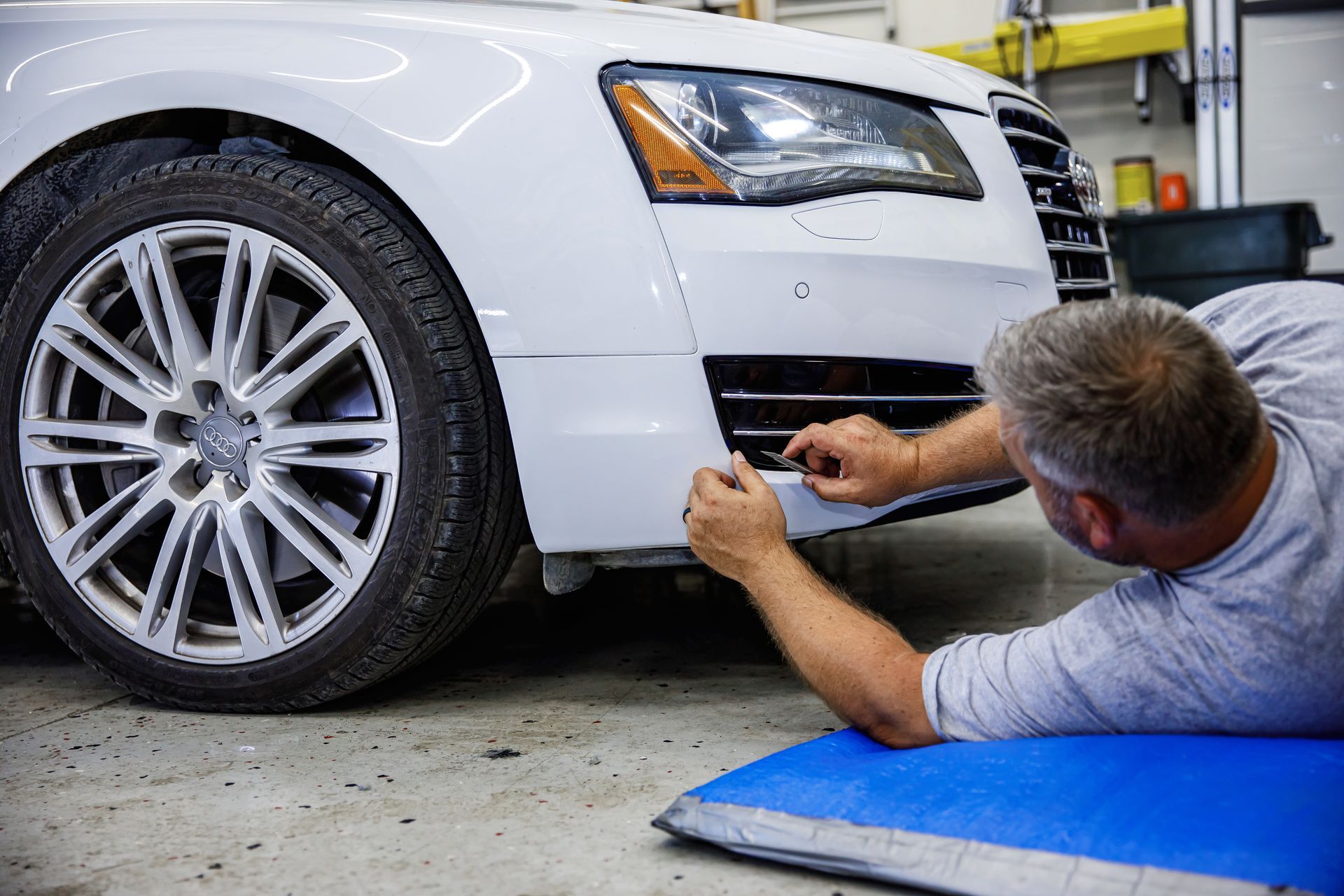 A man is applying a protective film to the headlights of a mercedes benz.