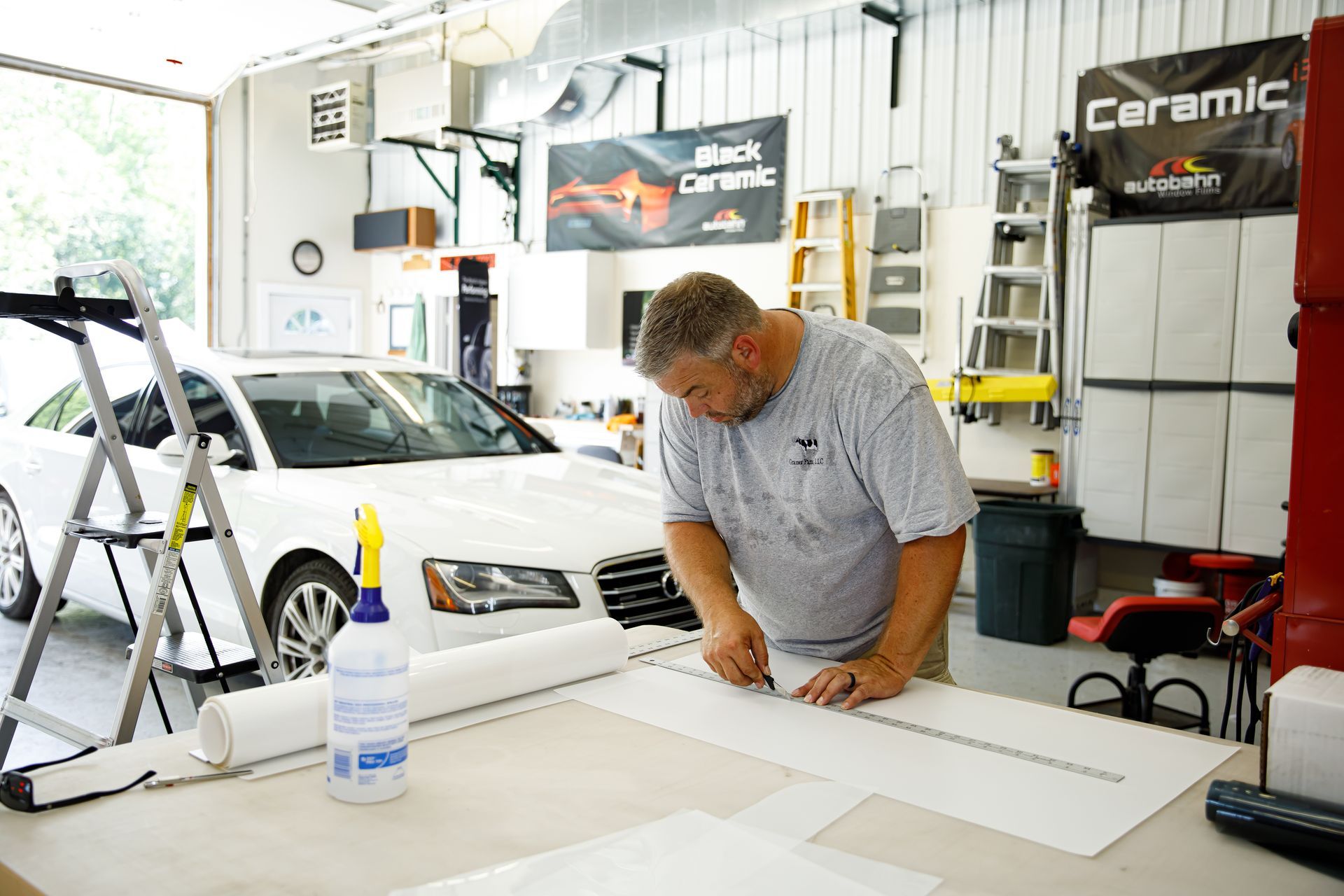 A man is applying protective film to the hood of a car.