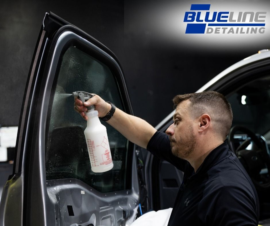 A person is applying tinted glass to a car window.