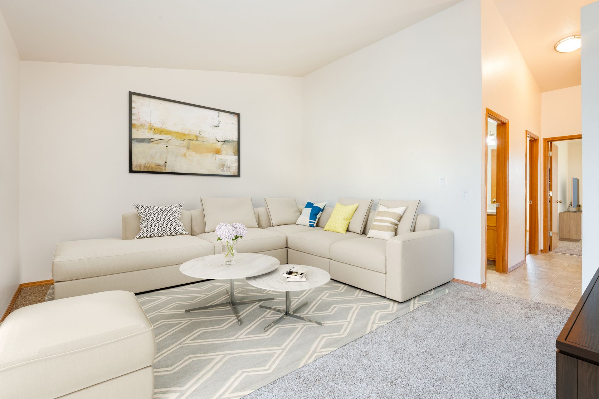 View of living room with tall ceilings and peek of the hallway to the right.