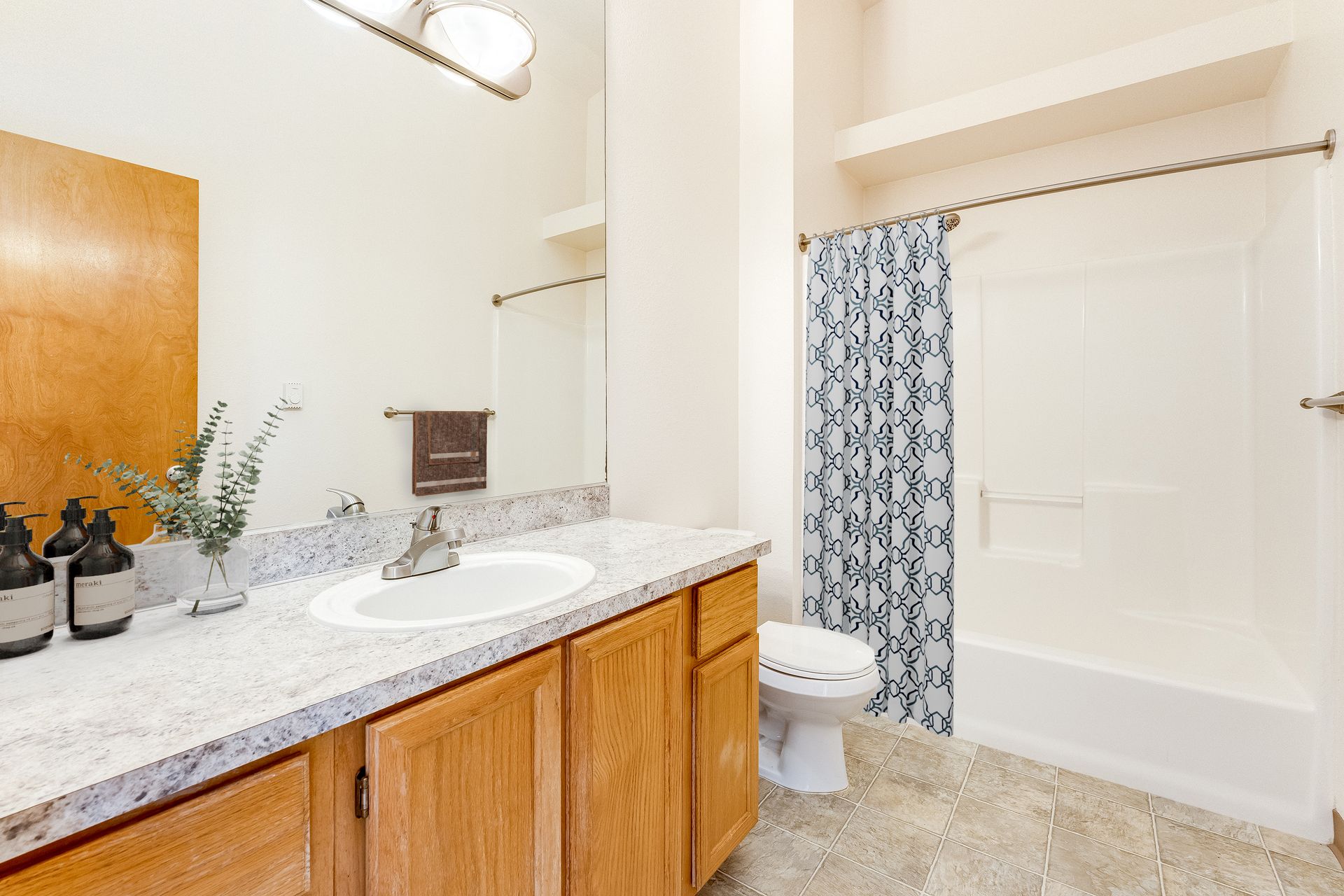 Spacious bathroom with large mirror and curved shower curtain rod.