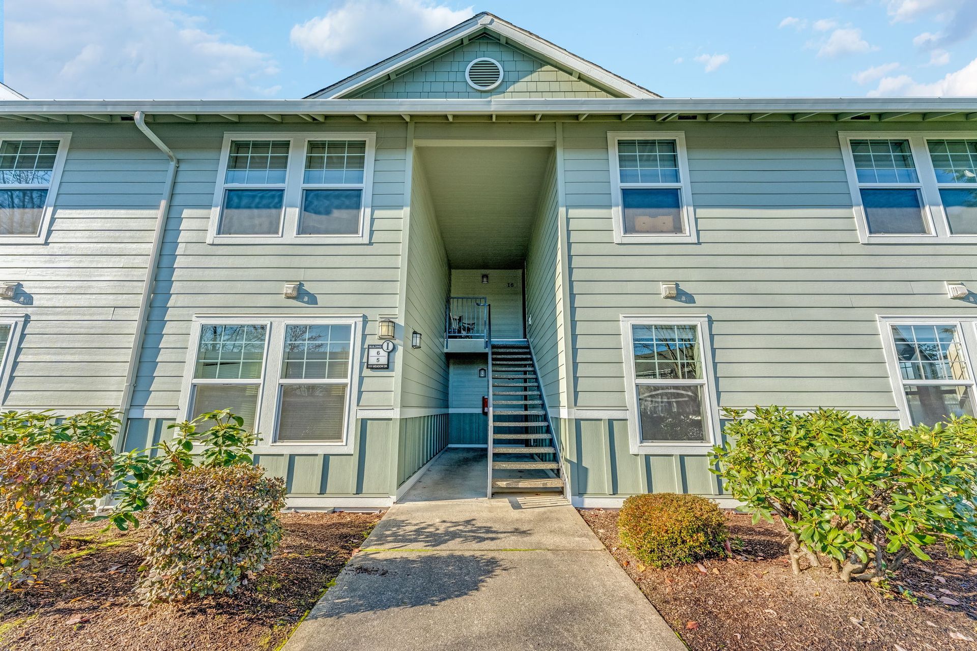 Exterior of apartment looking into and entryway with two apartment doors on the bottom and two at the top of the stairwell.