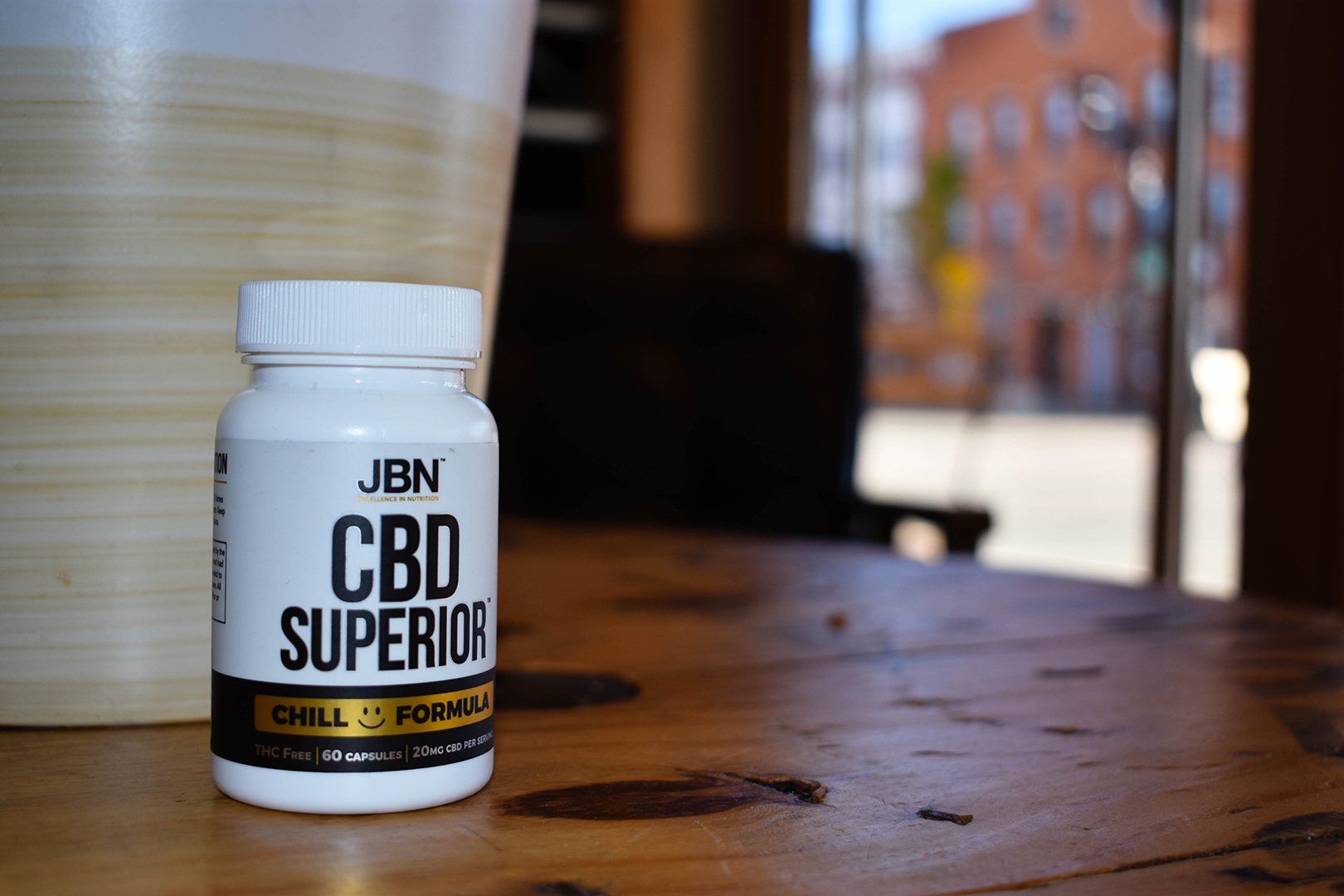 JBN's CBD supplement product on a wood table with a blurred background