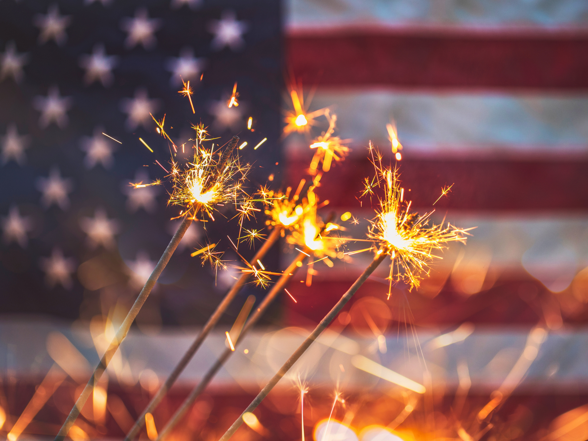 Sparkler fireworks in front of a blurred American flag background