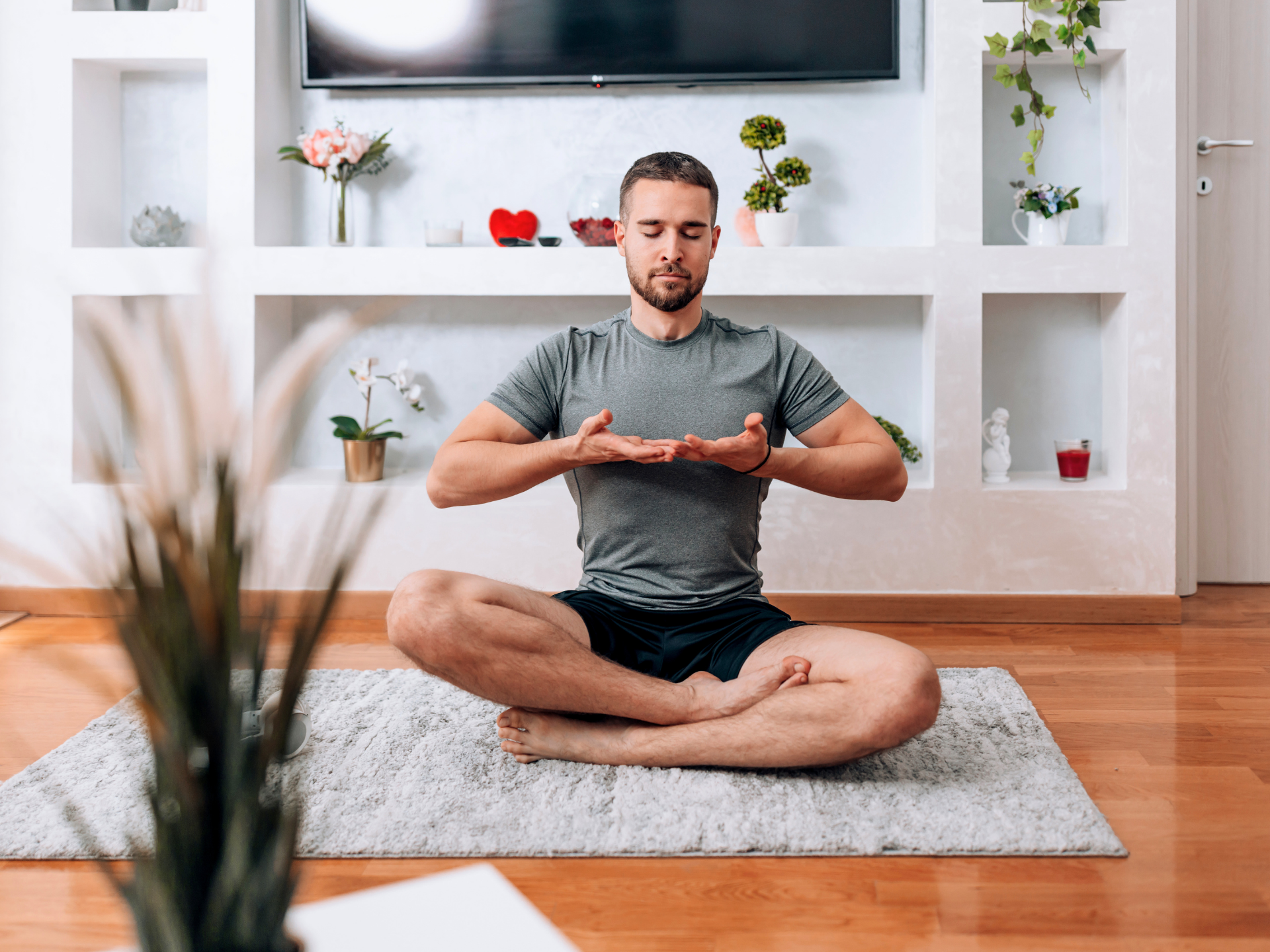 Person meditating cross-legged on a rug in a bright living room