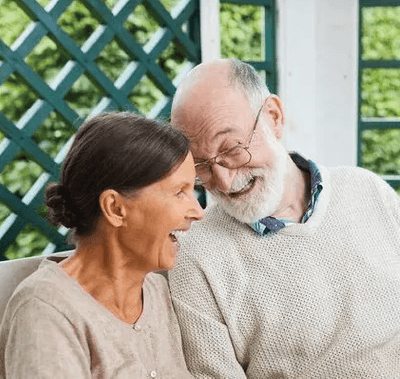 A man and a woman are sitting on a bench reading a newspaper.