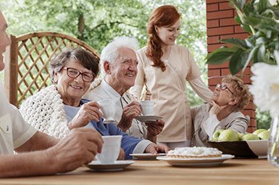 A group of elderly people are sitting at a table drinking coffee.
