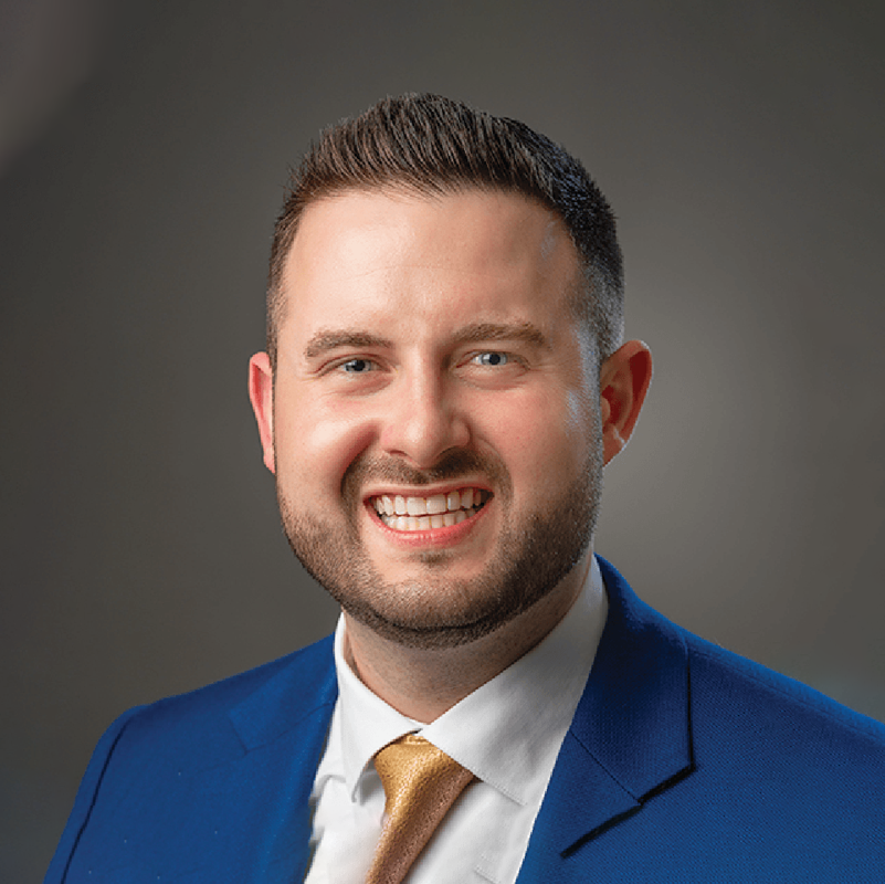A man in a blue suit and tie is smiling for the camera.