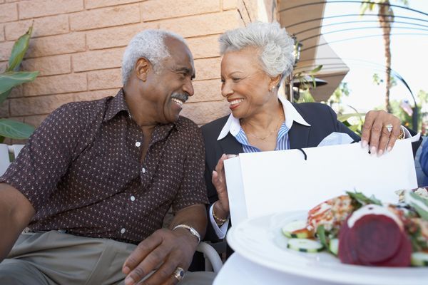 A man and woman are sitting at a table with a plate of food.