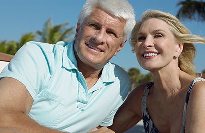 A man and a woman are sitting next to each other on a beach.