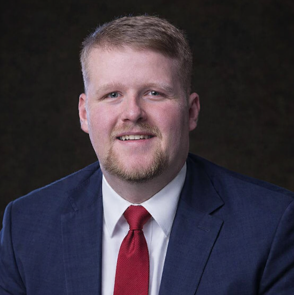 A man in a suit and tie is smiling for the camera