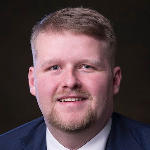 A man in a suit and tie is smiling for the camera