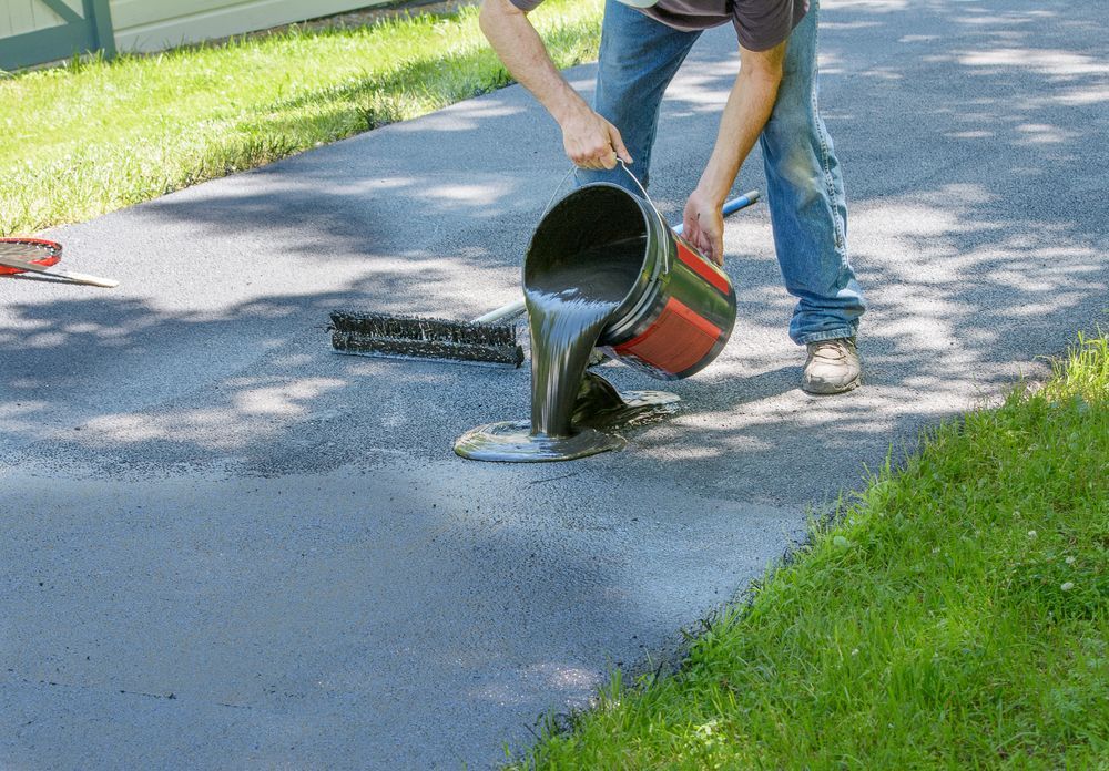 Person Pouring Asphalt Sealant Onto a Driveway — Totally Building and Maintenance in Kincumber, NSW