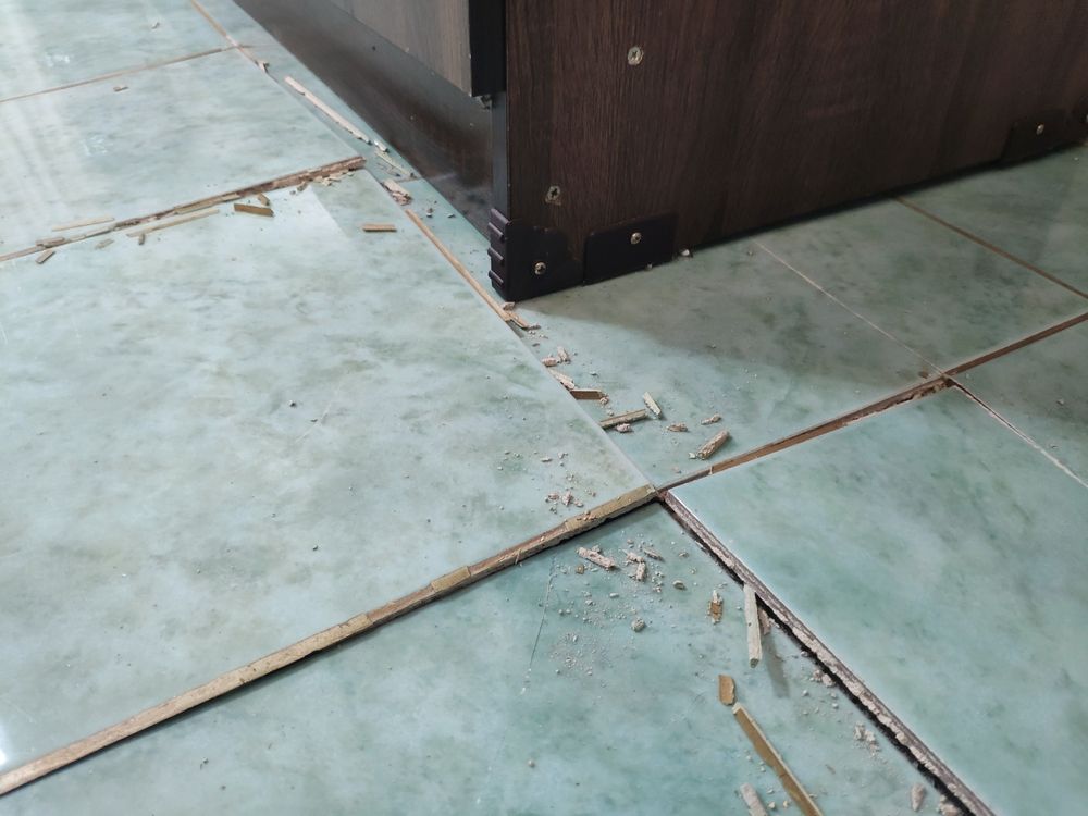 Damaged Tile Floor With Debris Near the Corner — Totally Building and Maintenance in Avoca, NSW