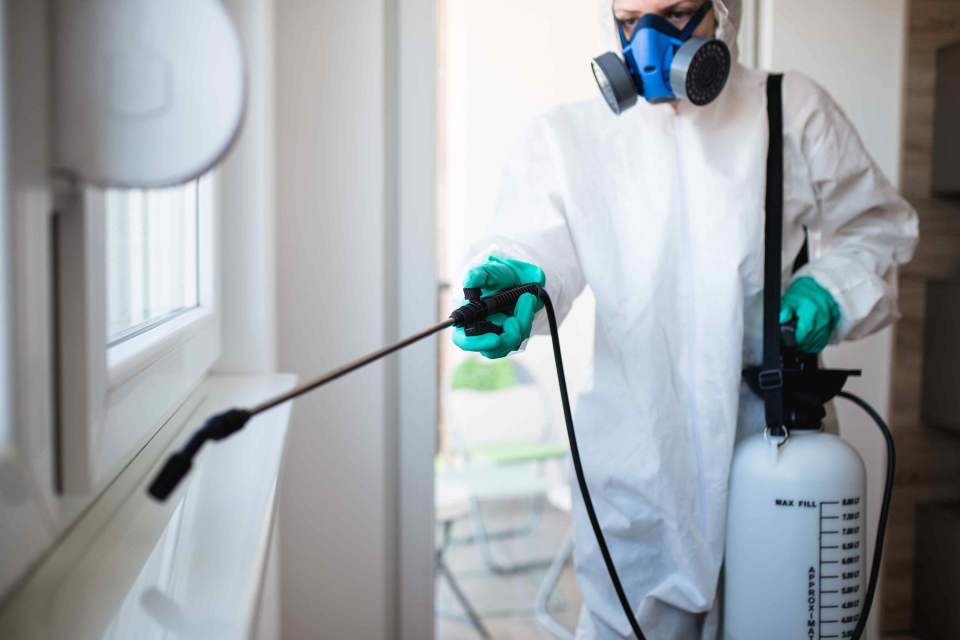 exterminator spraying windowsill with insecticide