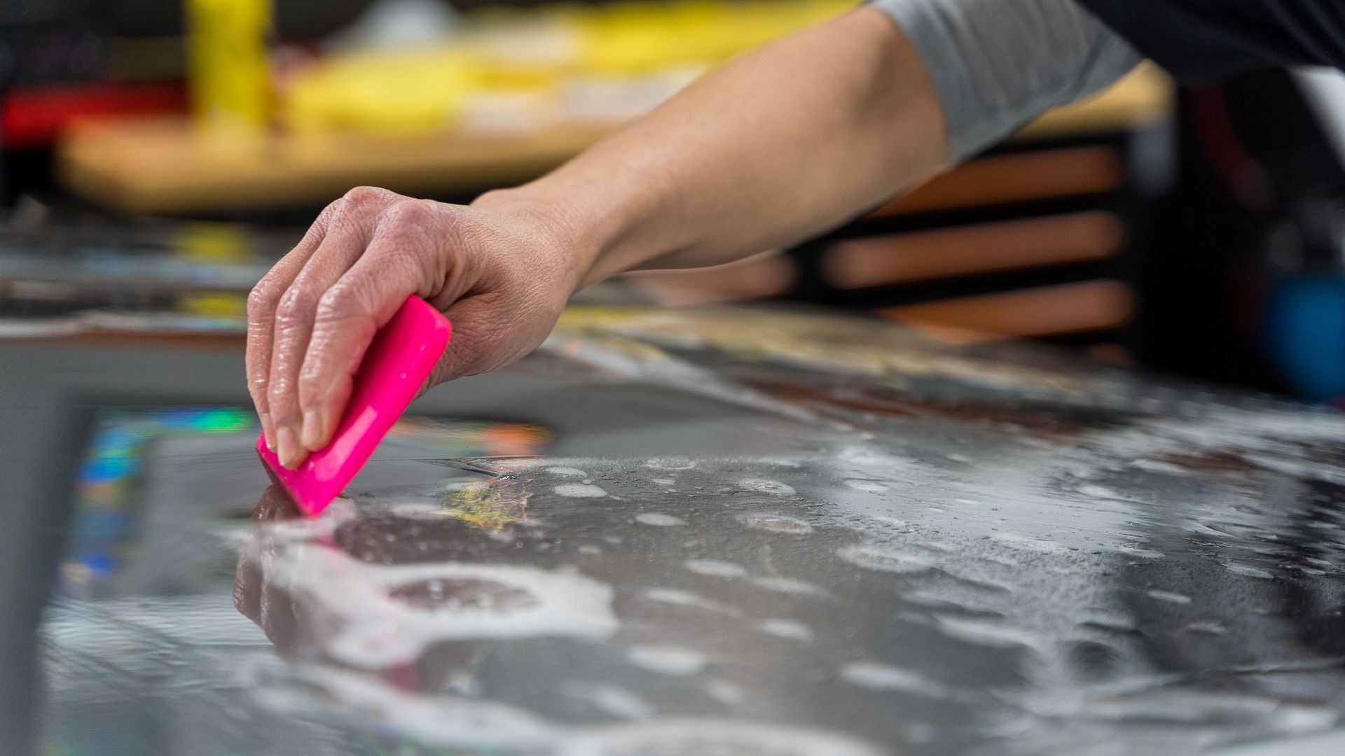 a person is using a pink squeegee to clean a surface