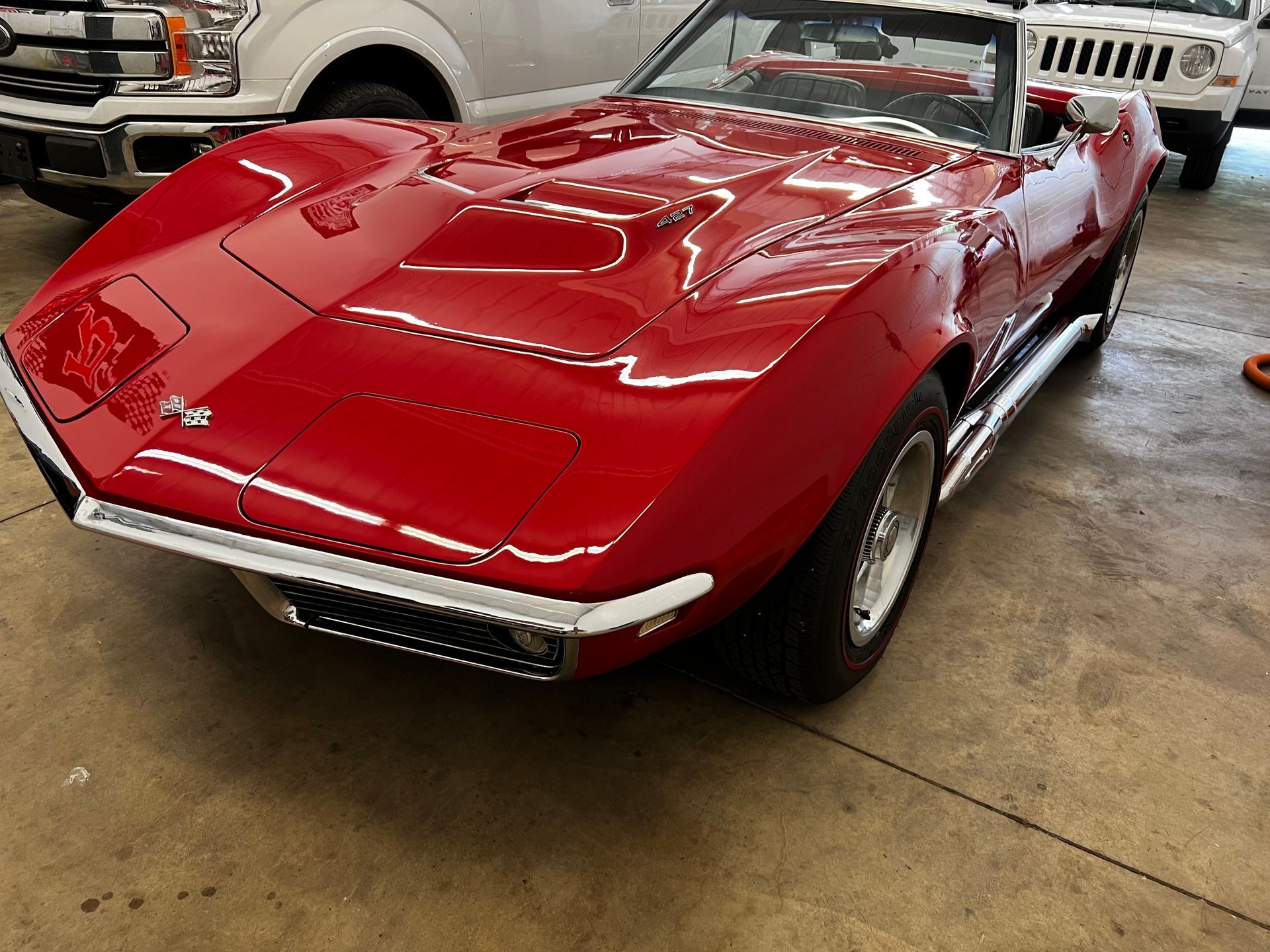 a red corvette is parked next to a white truck