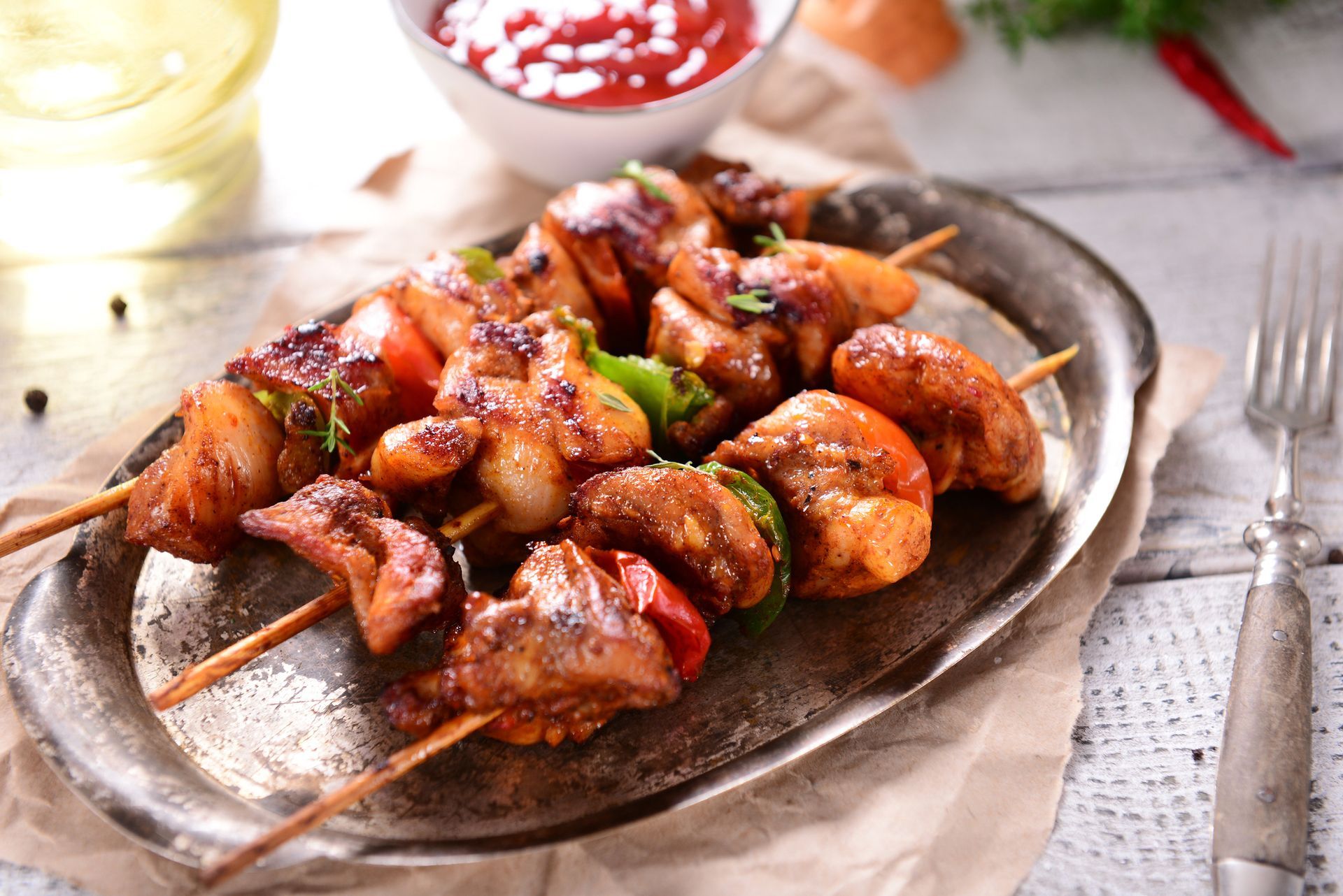 Un piatto di cibo con carne e verdure infilzate su uno spiedino su un tavolo.