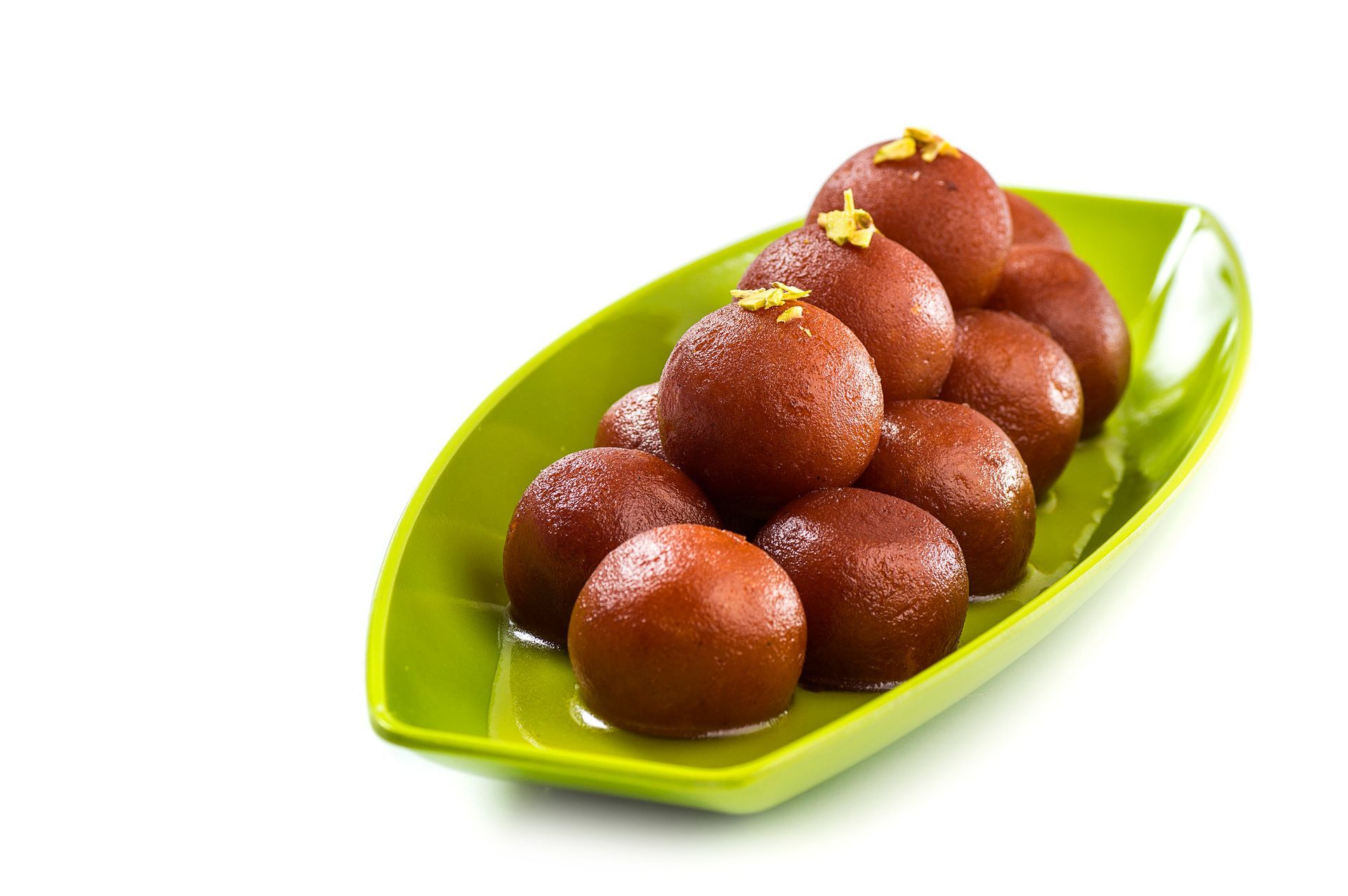 Un piatto verde con sopra dei gulab jamun su uno sfondo bianco.
