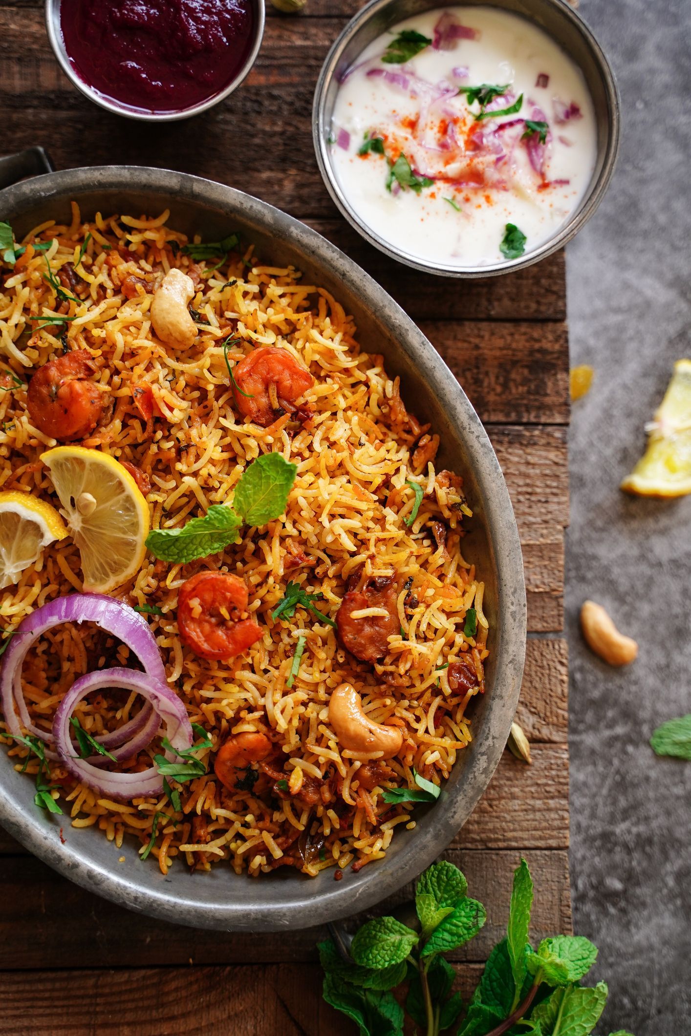 Una ciotola di riso con gamberi e cipolle su un tavolo di legno.