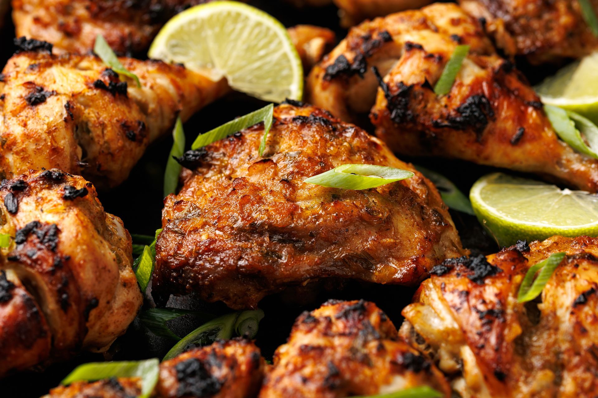Primo piano di un piatto di pollo alla griglia con lime e cipollotti.