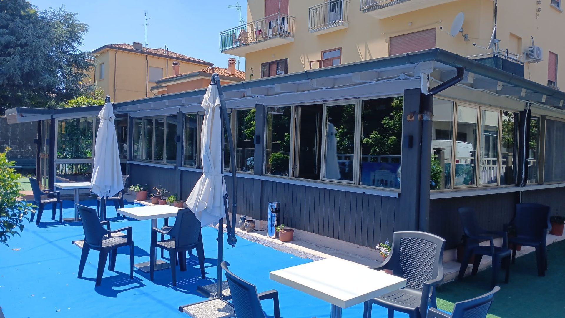 Un patio con tavoli, sedie e ombrelloni di fronte a un edificio.