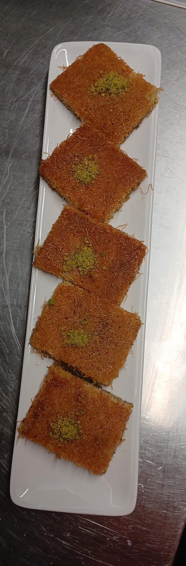 Un piatto bianco sormontato da quadratini di cibo su un tavolo.