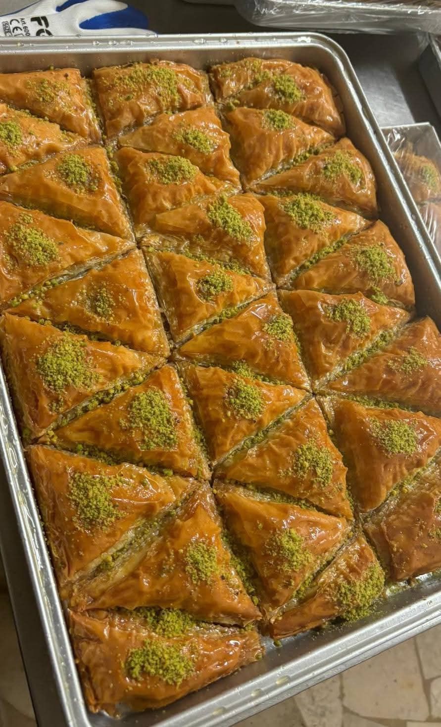 Un vassoio di baklava con pistacchi sopra è appoggiato su un tavolo.
