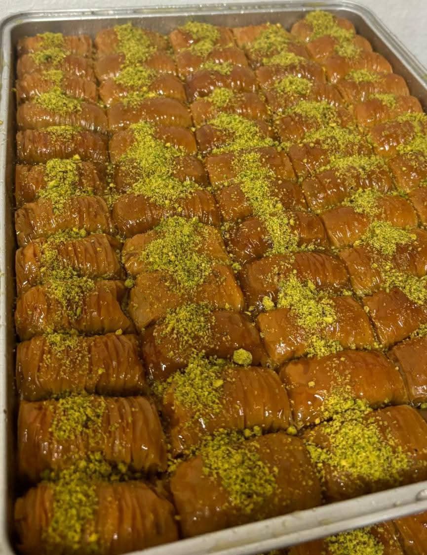 Un vassoio di baklava con pistacchi sopra è appoggiato su un tavolo.