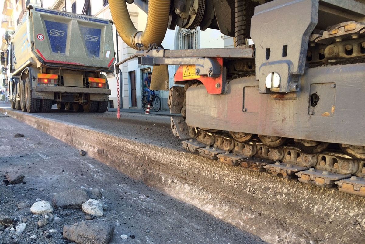 Pavimentatrice stradale che stende l'asfalto accanto a un camion. Costruzione di strade.