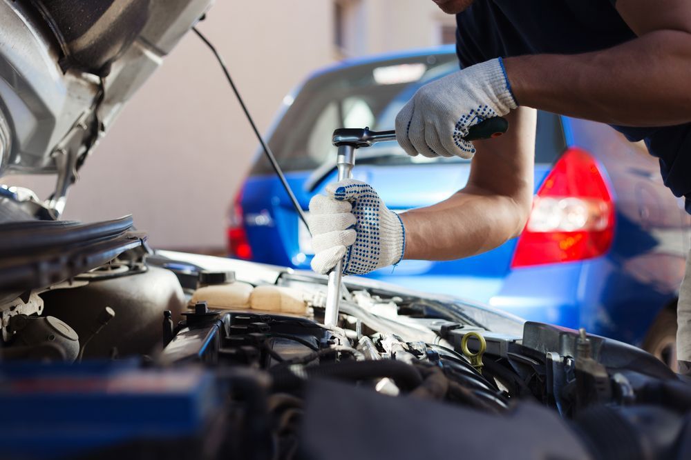A man is working on the engine of a car with the hood open  — Oaks Automotive Pty Ltd in Oak Flats, NSW