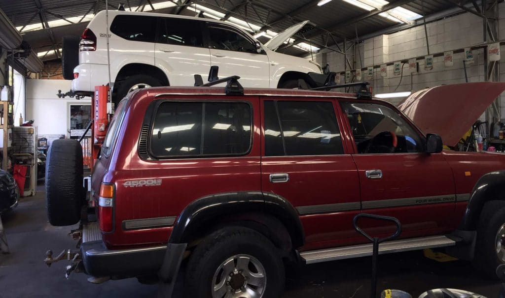 Red Suv is Parked in a Garage Next to a White Suv — Oaks Automotive Pty Ltd in Oak Flats, NSW