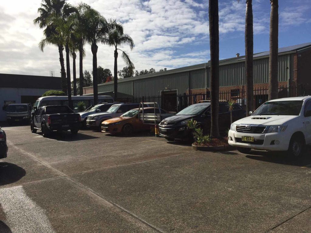 Row of Cars Are Parked in a Parking Lot Next to Palm Trees — Oaks Automotive Pty Ltd in Oak Flats, NSW
