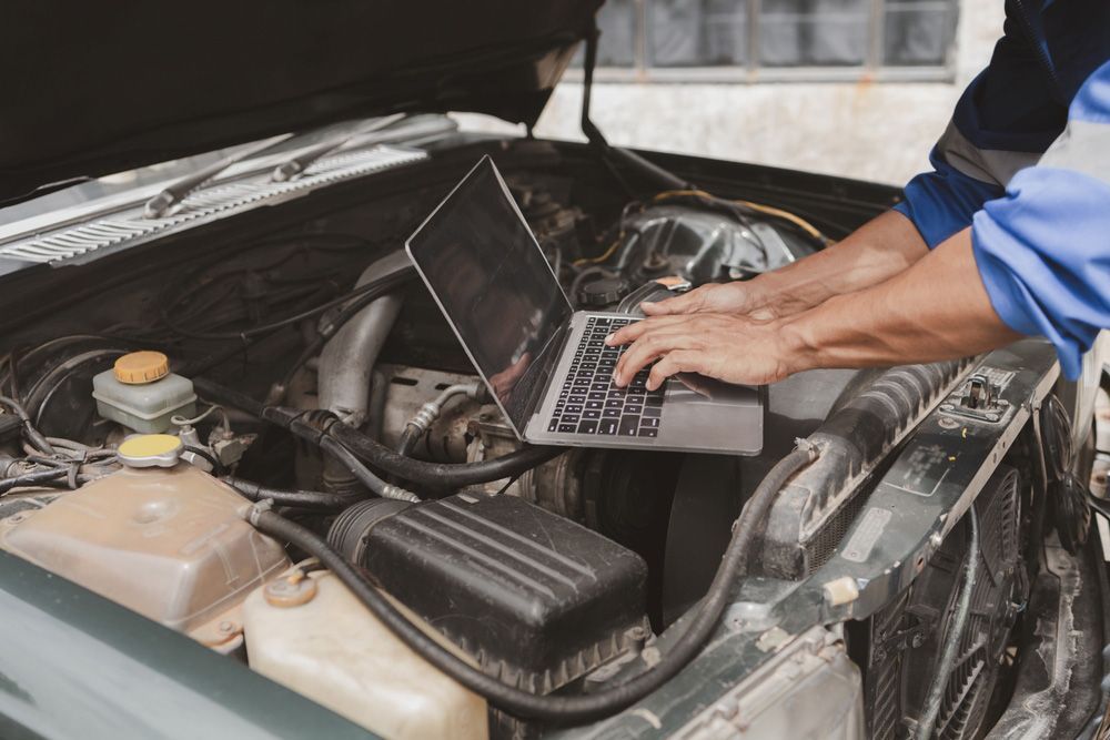 Man is Working on a Car Engine With a Laptop — Oaks Automotive Pty Ltd in Oak Flats, NSW