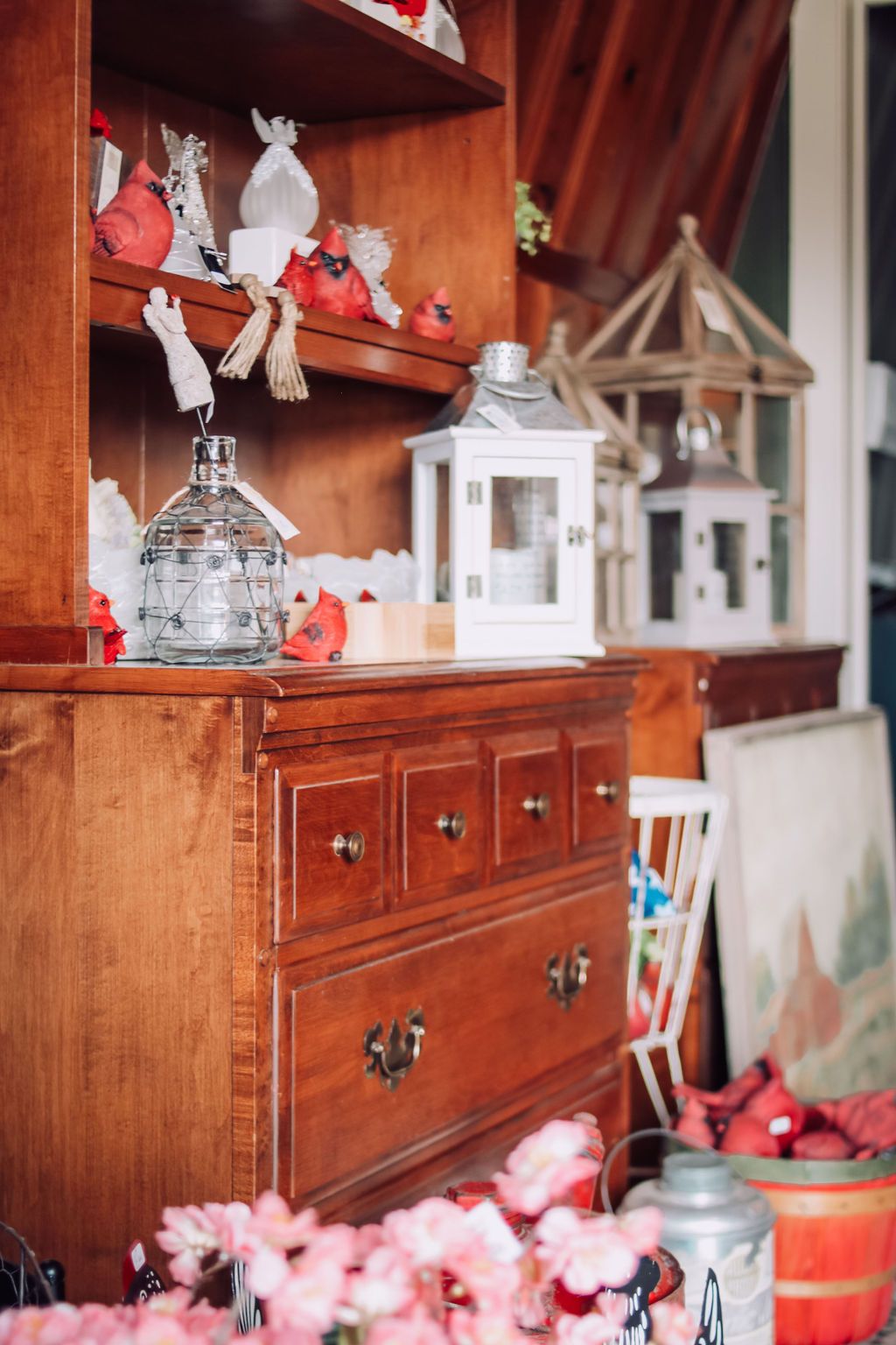 Wooden cabinet with drawers and shelves holding decorative items: lanterns, figurines, and a vase.